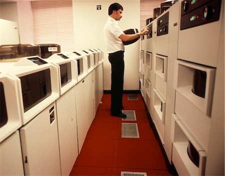 1970s 1980s COMPUTER TECHNICIAN CHANGE REEL ON MAIN FRAME COMPUTER RED & WHITE ROOM Stock Photo - Rights-Managed, Code: 846-02794910