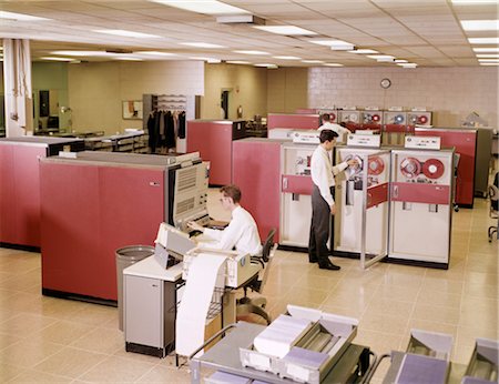 fuerza laboral - 1960s TWO MEN IN OFFICE WORKING AT MAINFRAME REEL TO REEL COMPUTERS Foto de stock - Con derechos protegidos, Código: 846-02794925
