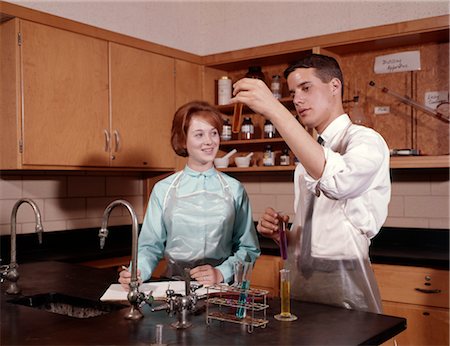 1960s 2 STUDENTS IN CHEMISTRY LAB BOY HOLD UP TEST TUBE GIRL TAKE NOTES HIGH SCHOOL LABORATORY SCIENCE Stock Photo - Rights-Managed, Code: 846-02795105