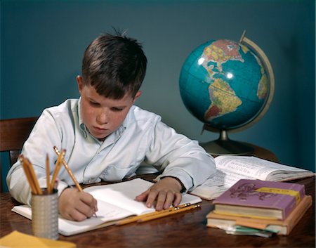 1960s 1970s BOY DOING HOMEWORK AT DESK WRITING NOTEBOOK BOOKS GLOBE Stock Photo - Rights-Managed, Code: 846-02795173