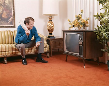 rolled up - 1960s MAN SITTING ON SOFA HOLDING ROLLED UP NEWSPAPER AND LOOKING AT LIVING ROOM TELEVISION Stock Photo - Rights-Managed, Code: 846-02795223