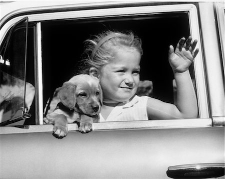 1950s LITTLE BLOND GIRL HOLDING A PUPPY DOG RIDING IN AN AUTOMOBILE WAVING HER HAND Stock Photo - Rights-Managed, Code: 846-02795385