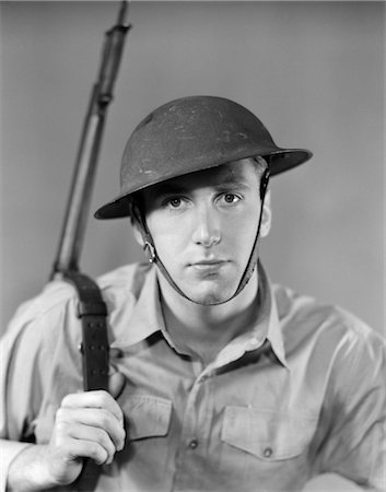 1940s PORTRAIT OF AMERICAN MAN SOLDIER SERIOUS EXPRESSION GUN RIFLE ON SHOULDER HELMET WITH CHIN STRAP WW2 ARMY VINTAGE Foto de stock - Con derechos protegidos, Código: 846-02795407