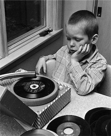 1960s 1970s BOY WITH BUZZ HAIRCUT CHIN IN HAND SITTING AT TABLE LISTENING TO MUSIC ON SMALL PORTABLE 45 RPM PHONOGRAPH RECORD PLAYER Foto de stock - Con derechos protegidos, Código: 846-02795459