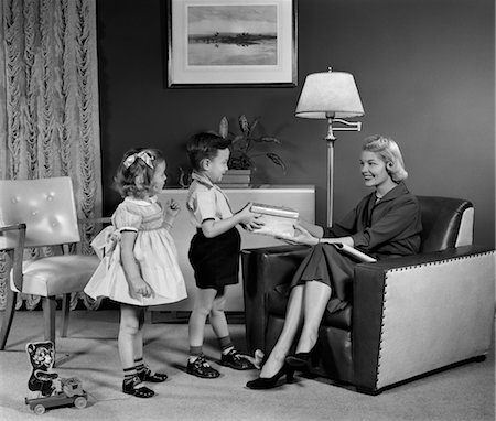 family room and vintage - 1950s LITTLE BOY AND GIRL SON AND DAUGHTER GIVING WOMAN MOTHER SITTING IN LIVING ROOM A GIFT PRESENT Stock Photo - Rights-Managed, Code: 846-02795477