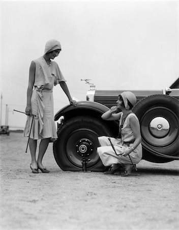 1930s TWO WOMEN CONFRONT AN AUTOMOBILE FLAT TIRE Foto de stock - Direito Controlado, Número: 846-02795486