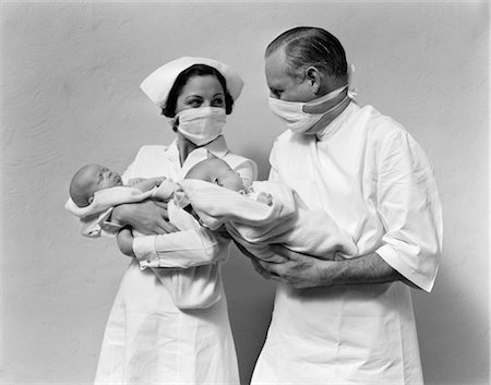 1930s 1940s MAN DOCTOR WOMAN NURSE WEARING STERILE MASKS HOLDING NEWBORN INFANT TWIN BABIES Foto de stock - Con derechos protegidos, Código: 846-02795577