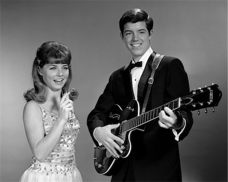 1960s TEENAGE ENTERTAINMENT DUO MAN PLAYING GUITAR AND WOMAN SINGING HOLDING MICROPHONE Foto de stock - Con derechos protegidos, Código: 846-02795615