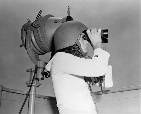 sailor (occupation) - ANNÉES 1940 LA SECONDE GUERRE MONDIALE VINTAGE MARIN BLANC UNIFORME CASQUE TENIR JUMELLES DEBOUT À CÔTÉ DE LUMIÈRE MESSAGE CLIGNOTANT Photographie de stock - Rights-Managed, Code: 846-02795717