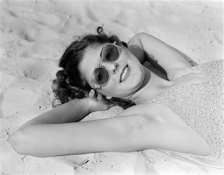 1930s WOMAN IN SUNGLASSES LYING ON BEACH WEARING BATHING SUIT Stock Photo - Rights-Managed, Code: 846-02795822