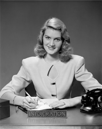 simsearch:846-02795848,k - 1950s WOMAN SITTING AT INFORMATION DESK IN OFFICE WRITING IN APPOINTMENT BOOK Stock Photo - Rights-Managed, Code: 846-02795835