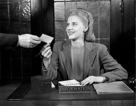 receptionist at desk - 1940s YOUNG SMILING WOMAN APPOINTMENT SECRETARY RECEPTIONIST ACCEPTING BUSINESS CARD FROM MAN'S HAND Stock Photo - Rights-Managed, Code: 846-02795854