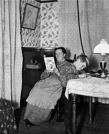 simsearch:846-02795985,k - 1900s TURN OF THE CENTURY BOY PLAYING AT TABLE IN SITTING ROOM WITH MOTHER IN CHAIR BEHIND HIM READING Stock Photo - Rights-Managed, Code: 846-02795889