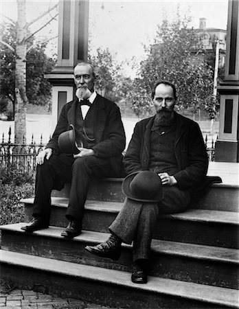 1890s TURN OF THE CENTURY TWO BEARDED MEN FATHER AND SON IN SUITS HOLDING BOWLER HATS SITTING ON STAIRS IN FRONT OF HOUSE Stock Photo - Rights-Managed, Code: 846-02795914