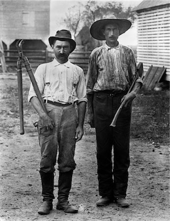 1890s 1900s 2 MEN ON FARM IN WORK CLOTHES ONE HOLDING PRUNER & ONE HOLDING AX Foto de stock - Con derechos protegidos, Código: 846-02795910