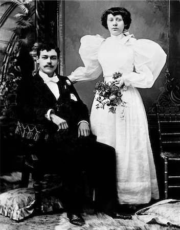 photography 1900 portrait black white - EARLY 1900s FORMAL PORTRAIT OF BRIDE AND GROOM MAN SEATED WOMAN STANDING INDOOR Stock Photo - Rights-Managed, Code: 846-02795961