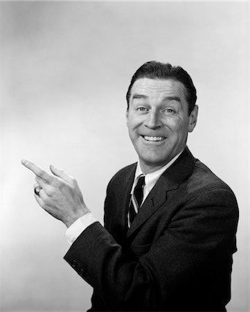 person's - 1960s SMILING HAPPY MAN BUSINESS SPOKESPERSON IN SUIT AND TIE LOOKING AT CAMERA POINTING HAND AND INDEX FINGER Stock Photo - Rights-Managed, Code: 846-02796147