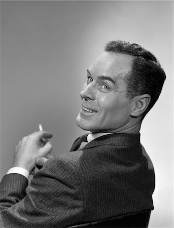 portrait businessman black and white - 1950s 3 4 PROFILE MAN LOOKING OVER HIS SHOULDER CIGARETTE IN HAND SMILING Stock Photo - Rights-Managed, Code: 846-02796173