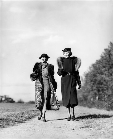 ANNÉES 1930 DEUX FEMMES MARCHANT SUR RURAL ROUTE PORTANT UN LÉOPARD PELISSE L'AUTRE PORTE MANTEAU DE FOURRURE A VOLÉ EN PLEIN AIR Photographie de stock - Rights-Managed, Code: 846-02796191