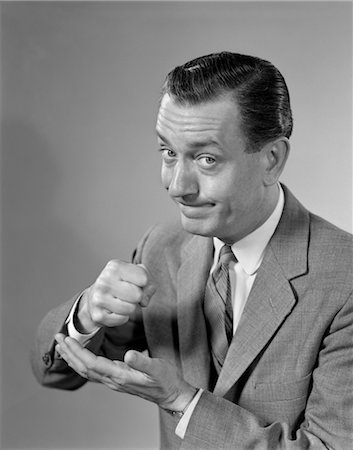portrait businessman black and white - 1960s DETERMINED MAN BUSINESSMAN SERIOUS EXPRESSION POUNDING FIST INTO PALM OF HIS HAND Stock Photo - Rights-Managed, Code: 846-02796209