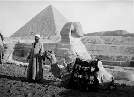 ANNÉES 1930 ANNÉES 1920 TOURIST ATTRACTION CAMEL ET ROBE ARABE DE PORTE CONDUCTEUR HOMME AU SPHINX ET LES PYRAMIDES DE GIZEH EN ÉGYPTE Photographie de stock - Rights-Managed, Code: 846-02796305