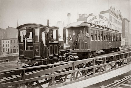 1880s LOCOMOTIVE & ONE PASSENGER CAR RUNNING ON EAST 42nd STREET GROUP OF MEN ON BOARD GRAND UNION HOTEL IN BACKGROUND Stock Photo - Rights-Managed, Code: 846-02796326