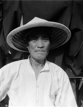 simsearch:846-02796405,k - 1930s OLD RICKSHAW COOLIE PORTRAIT UNSMILING WEARING STRAW HAT WORKER MEAN UNHAPPY EXPRESSION YOKOHAMA JAPAN Fotografie stock - Rights-Managed, Codice: 846-02796345