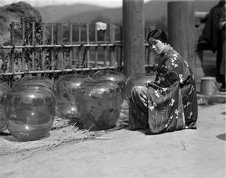 1930s UNSMILING JAPANESE WOMAN IN KIMONO KNEELING BY GROUP LARGE GOLD FISH BOWLS STREET GOLDFISH MARKET IN KOBE JAPAN Stock Photo - Rights-Managed, Code: 846-02796359