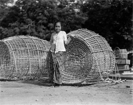 simsearch:846-02796405,k - ANNÉES 1930 PETITE FEMME AUTOCHTONE PERMANENT PAR DEUX GROS POISSONS JAPONAIS PIÈGES PANIERS DE PÊCHE BATAVIA JAVA INDONÉSIE Photographie de stock - Rights-Managed, Code: 846-02796374