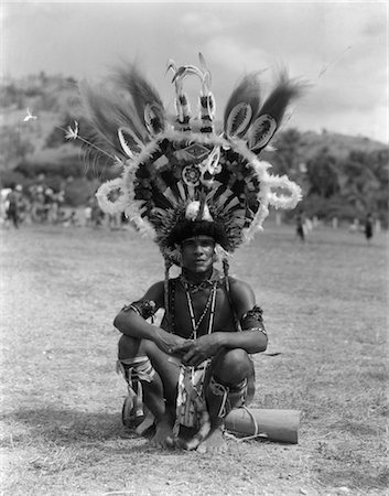 simsearch:846-02796389,k - 1920s 1930s PORTRAIT NATIVE MAN IN ELABORATE FEATHERED HEADDRESS COSTUME SITTING ON GROUND PORT MORESBY NEW GUINEA Foto de stock - Con derechos protegidos, Código: 846-02796386