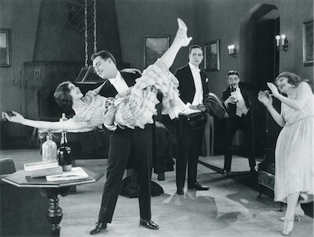 1920s MOVIE STILL OF WILD PARTY WITH WOMAN FLAPPER TURNED UPSIDE-DOWN IN ARMS OF MAN DANCING Foto de stock - Con derechos protegidos, Código: 846-02796466