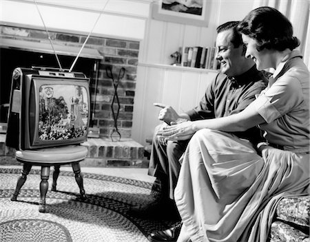 1950s COUPLE HUSBAND AND WIFE WATCHING TV IN LIVING ROOM SMILING INDOOR Stock Photo - Rights-Managed, Code: 846-02796684