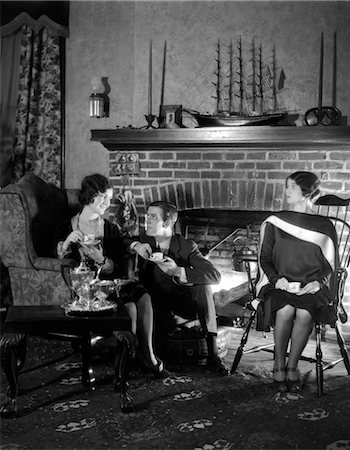 simsearch:846-02795744,k - 1920s MAN SITTING BETWEEN TWO WOMEN FLIRTING WITH ONE WOMAN IGNORING THE OTHER DRINKING TEA FIREPLACE IN BACKGROUND Foto de stock - Con derechos protegidos, Código: 846-02796694