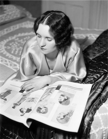 1920s 1930s RECLINING WOMAN WITH MARCEL WAVE HAIR STYLE WEARING A LIGHT COLORED SILK SATIN ROBE READING A FASHION MAGAZINE Foto de stock - Con derechos protegidos, Código: 846-02796714