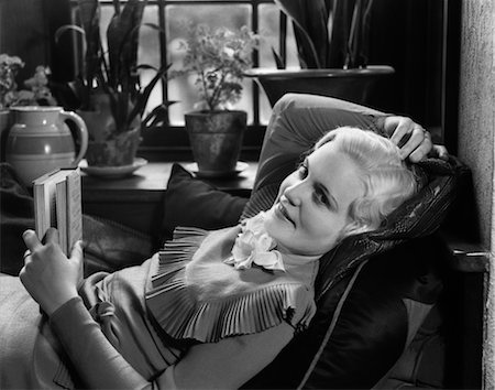 1930s BLOND WOMAN LYING BACK IN CHAIR HOLDING BOOK IN ONE HAND LOOKING OFF TO ONE SIDE CONTEMPLATIVE EXPRESSION Foto de stock - Con derechos protegidos, Código: 846-02796737