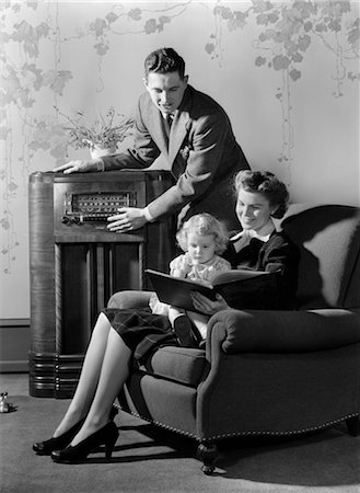 1930s 1940s FAMILY LISTENING TO RADIO WHILE MOTHER READS BOOK TO LITTLE GIRL SEATED IN HER LAP IN ARMCHAIR Foto de stock - Con derechos protegidos, Código: 846-02796731