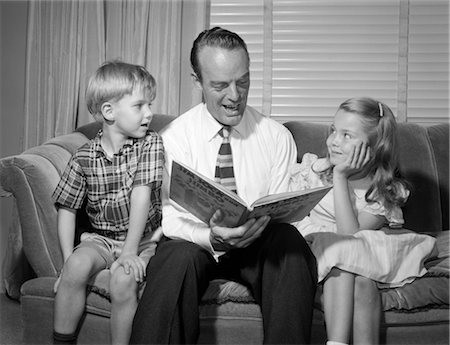 simsearch:846-02797198,k - 1950s FATHER WEARING DRESS SHIRT SLACKS TIE READING TO SON AND DAUGHTER SITTING ON SOFA SMILING Stock Photo - Rights-Managed, Code: 846-02796748