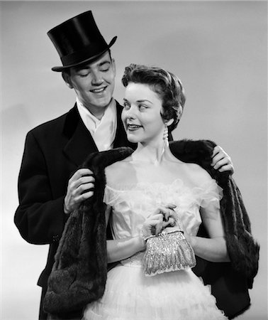 1950s COUPLE FORMAL ATTIRE MAN WEARING TOP HAT HELPING WOMAN IN EVENING CLOTHES WITH FUR STOLE Foto de stock - Con derechos protegidos, Código: 846-02796754