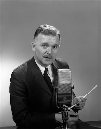 repórter - 1950s 1960s OLDER MAN SPEAKING INTO MICROPHONE HOLDING PAPERS RADIO TELEVISION NEWSMAN REPORTER ANNOUNCER Foto de stock - Direito Controlado, Número: 846-02796762