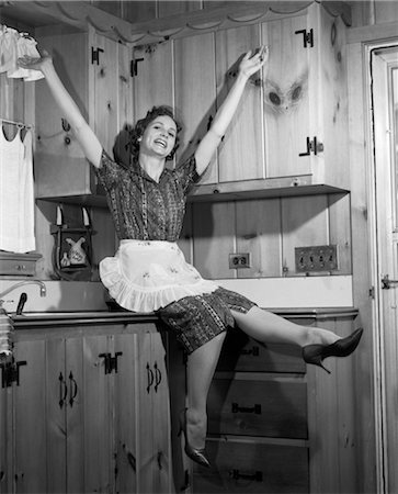 retro housewife apron - 1950s HOUSEWIFE SITTING ON COUNTERTOP KICKING FEET ARMS IN AIR Stock Photo - Rights-Managed, Code: 846-02796831