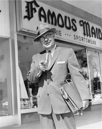 simsearch:846-02795869,k - HOMME DES ANNÉES 1950, POINTANT VERS LA CAMÉRA TENUE SERVIETTE SOUS LE BRAS DEVANT LE MAGASIN DE VÊTEMENTS DE SPORT VENDENT COSTUME CRAVATE CHAPEAU HOMME D'AFFAIRES Photographie de stock - Rights-Managed, Code: 846-02796893