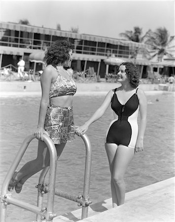 1930s 1940s TWO WOMEN IN BATHING SUITS STANDING BY SIDE OF POOL ONE LEANING ON POOL LADDER Stock Photo - Rights-Managed, Code: 846-02797038