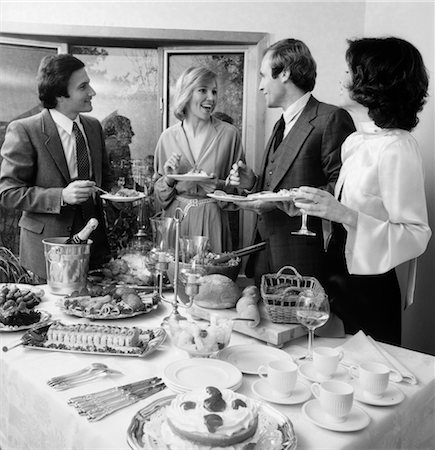 social gathering black and white picture - 1980s PAIR OF COUPLES CHATTING OVER FOOD & DRINKS AT BUFFET TABLE Stock Photo - Rights-Managed, Code: 846-02797160