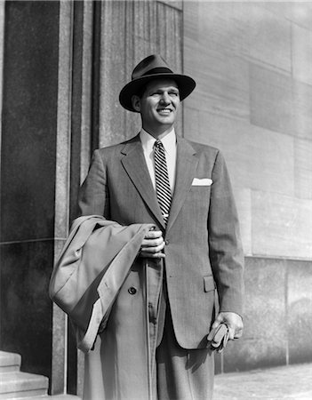 simsearch:846-02793337,k - 1950s YOUNG MAN IN SUIT AND STRIPED TIE WEARING HAT HOLDING COAT OVER HIS ARM GLOVES BUSINESSMAN PORTRAIT FASHION Foto de stock - Con derechos protegidos, Código: 846-02797192