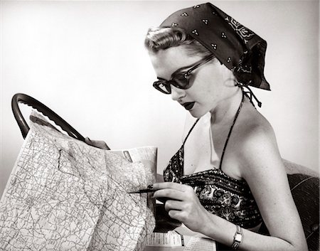 1950s WOMAN WEARING BANDANA SUNGLASSES & HALTER TOP MARKING ROAD MAP IN MOCK CAR SET-UP Foto de stock - Con derechos protegidos, Código: 846-02797221