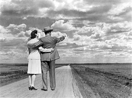 possibilities - 1940s COUPLE WITH ARMS AROUND EACH OTHER STANDING ON OPEN ROAD IN MIDDLE OF NOWHERE Foto de stock - Con derechos protegidos, Código: 846-02797238