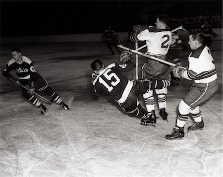 1950s HOCKEY GAME WITH ONE OF 4 PLAYERS IN FOREGROUND BEING KNOCKED DOWN BY 2 OPPOSING TEAM MEMBERS Foto de stock - Con derechos protegidos, Código: 846-02797243