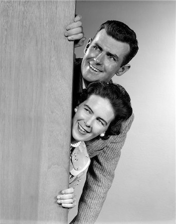 1950s COUPLE LOOKING OUT FROM BEHIND DOOR Stock Photo - Rights-Managed, Code: 846-02797298