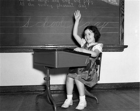 sitting at old fashioned desk - ANNÉES 1940 FILLE SOURIANTE ASSIS AU COMPTOIR LUI ÉLEVER MAIN BÉNÉVOLE DEMANDER RÉPONSE QUESTION TABLEAU NOIR CRAIE Photographie de stock - Rights-Managed, Code: 846-02797405