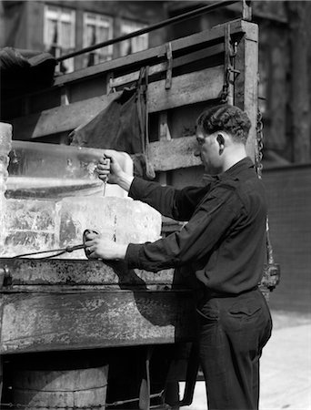 1930s ICE DELIVERY MAN STANDING AT BACK OF TRUCK HOLDING TONGS IN ONE HAND & PUTTING ICE PICK IN BLOCK OF ICE WITH OTHER Stock Photo - Rights-Managed, Code: 846-02797426